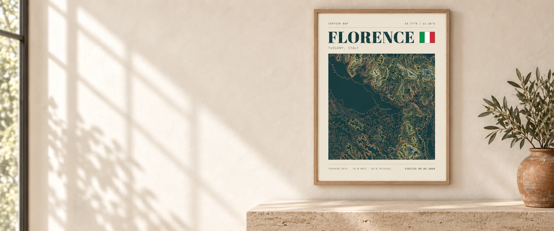 A framed Florence topographic poster in a natural oak frame above a travertine console