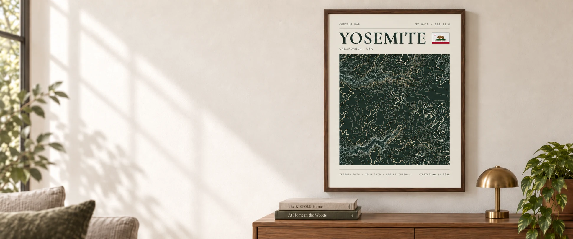 A framed Yosemite topographic poster above a walnut console in a sunlit room